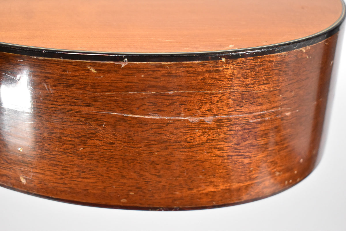 Close-up of the guitar's lower bout, showing two horizontal cracks, finish wear, and scratches on the dark brown wood side.