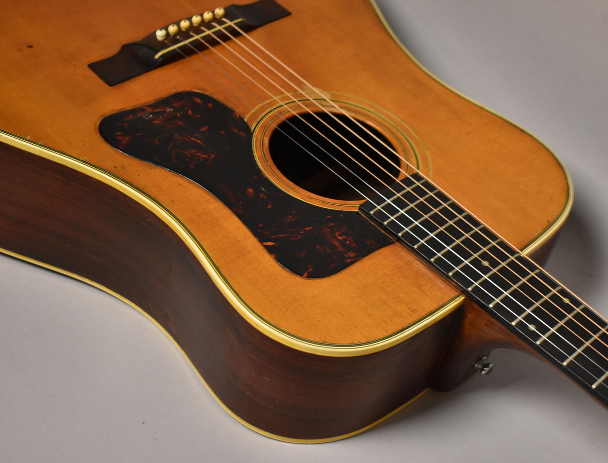 Close-up of the guitar's natural finish body and dark pickguard, showing light wear and the lower fretboard.