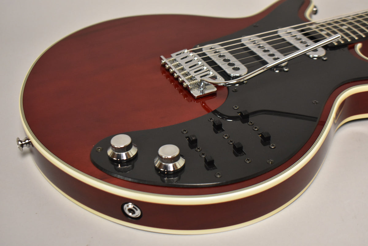 Cherry red guitar body with cream binding, black pickguard, chrome tremolo bridge, two chrome knobs, and six black switches.