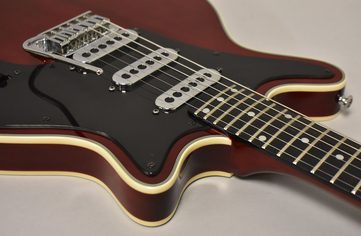 Close-up of the cherry red guitar body, showing the black pickguard, three chrome pickups, and part of the fretboard.