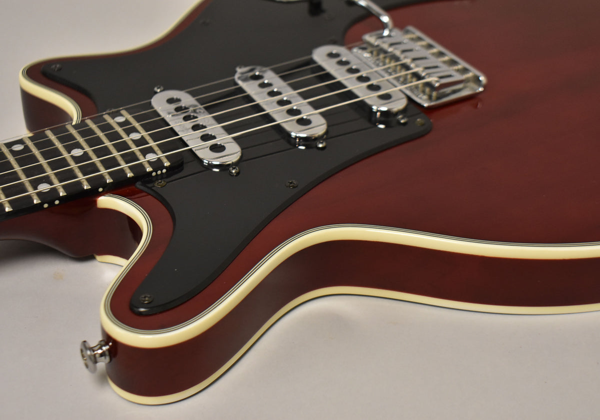 Close-up of the cherry red guitar body, showing the black pickguard, three chrome pickups, and cream binding along the edges.