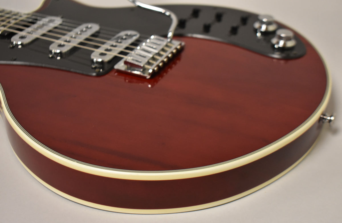 Close-up of the cherry red guitar body, showing the black pickguard with three chrome pickups, bridge, and two control knobs.