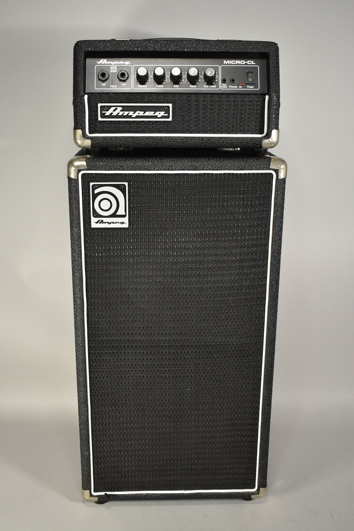 Full front view of a black textured amp head with 6 knobs and a matching speaker cabinet with white piping and chrome corner protectors.