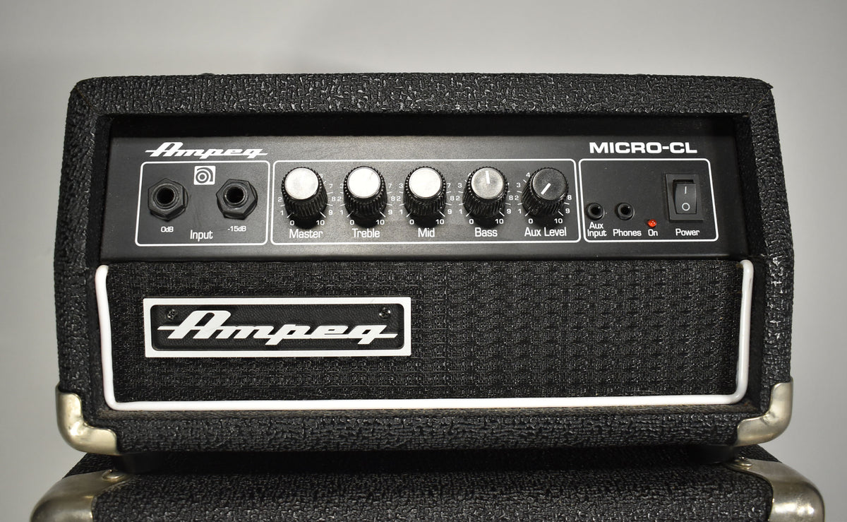 The black textured amp head, viewed from the front, features a control panel with input jacks, five knobs, and a power switch.