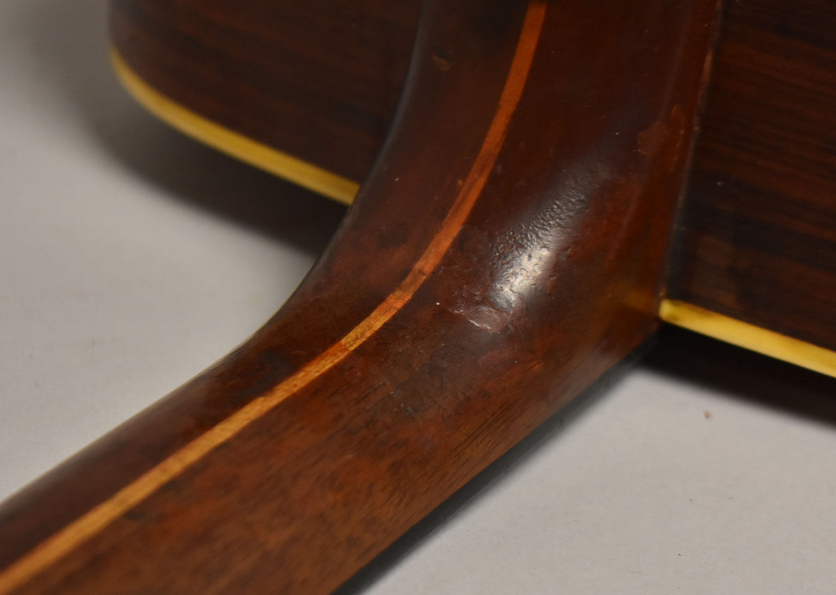 Close-up of the dark brown neck heel and lower neck, showing a light wood stripe and finish wear.