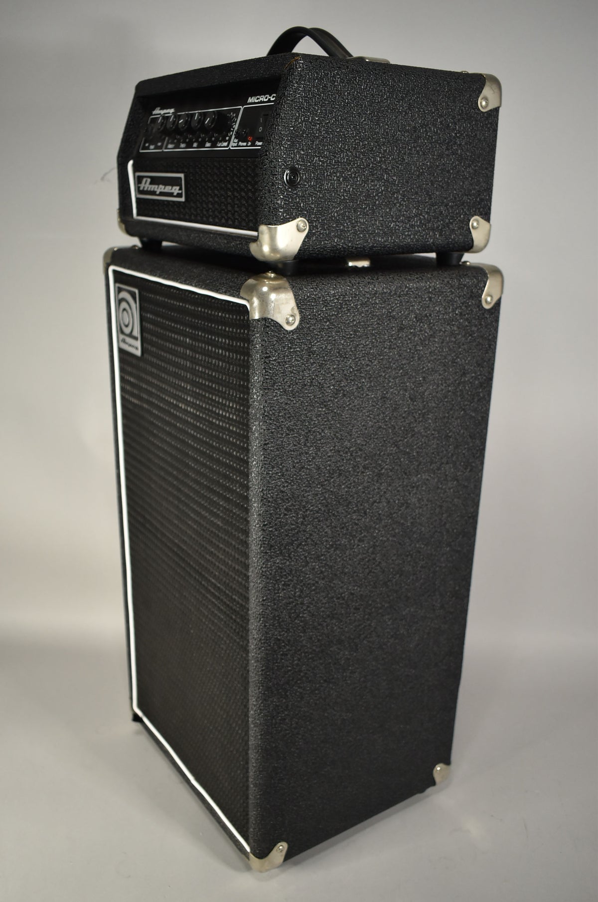 The black textured amp head sits atop the matching speaker cabinet, both with silver corner protectors, viewed from the front-right.