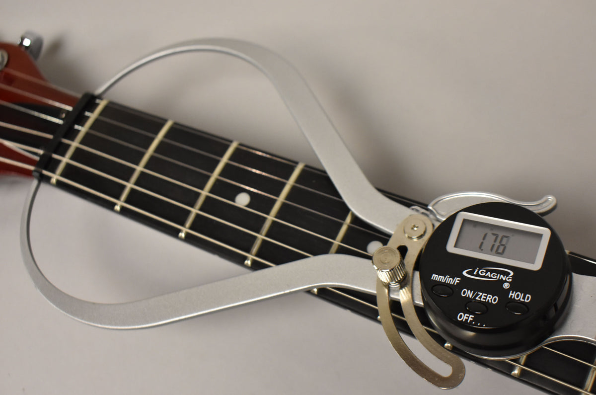 Close-up of the guitar's dark fretboard with white dot inlays, showing a silver digital string action gauge displaying "1.78".