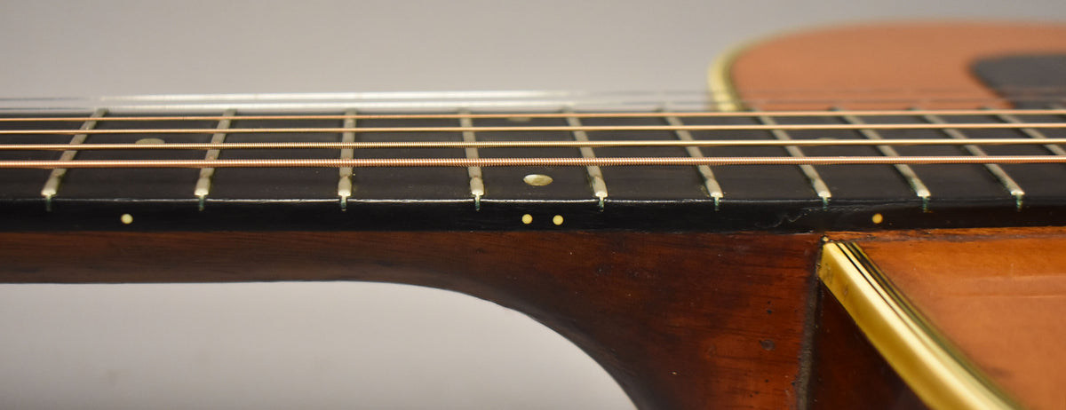 Close-up of the dark fretboard and neck, showing light fret wear, dot inlays, and the body's natural finish and binding.