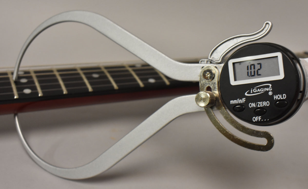 A digital caliper measures the fret height at 1.02mm on the dark rosewood fretboard with white dot inlays.