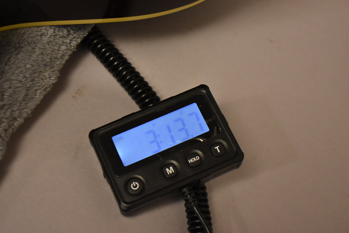 Close-up of a digital scale displaying "3.13.7" in blue, with a coiled black cable and a fuzzy gray cloth visible.