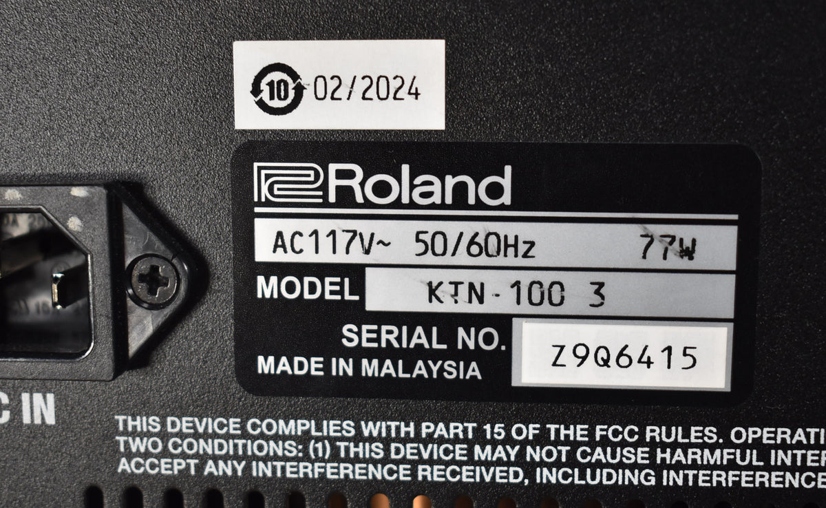 Close-up of the amp's textured black rear panel, showing the power input, a black Roland label, and a white sticker.