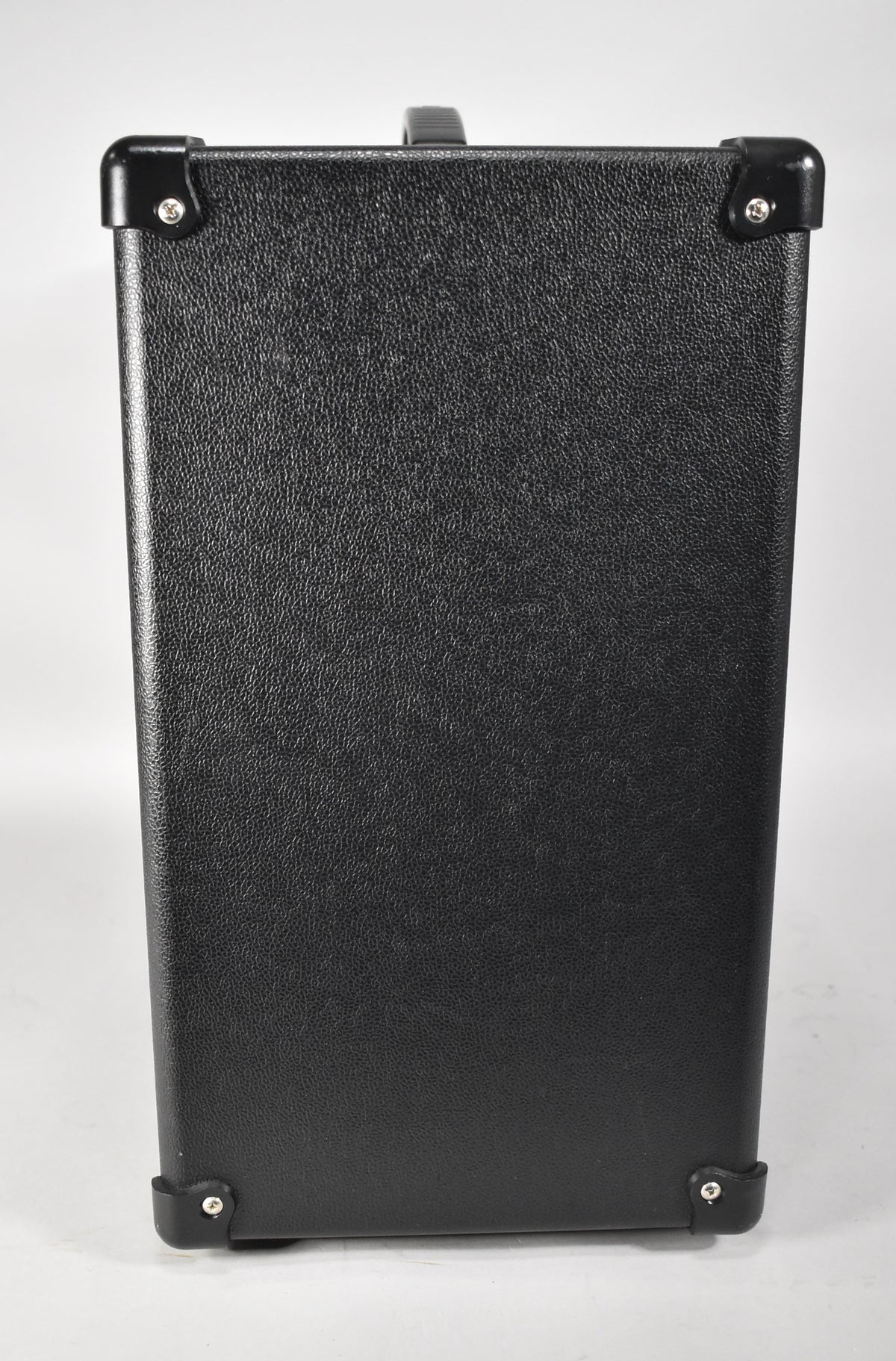 The black textured amp is viewed from the side, showing a top handle and four black corner protectors with silver rivets.