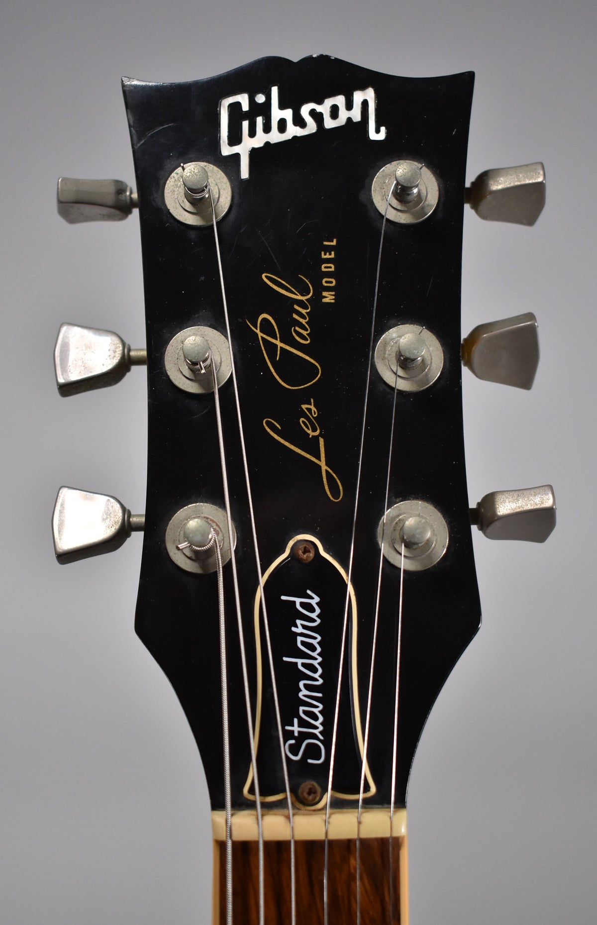 Close-up of the black headstock with six trapezoid tuners, showing light wear and a small chip on the top left edge.