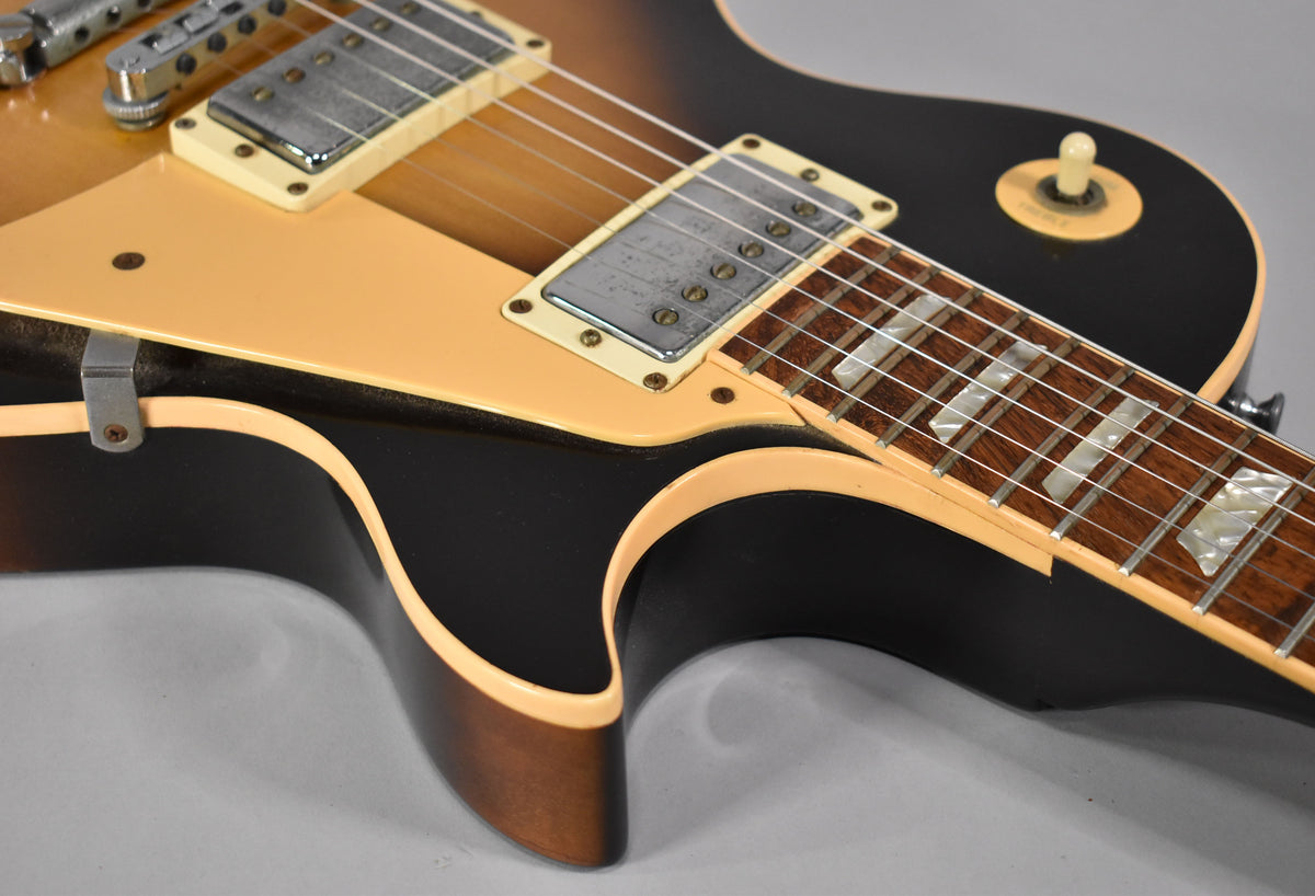 Close-up of the guitar's lower body, showing the tobacco sunburst finish, cream binding, pickguard, bridge pickup, and part of the fretboard.