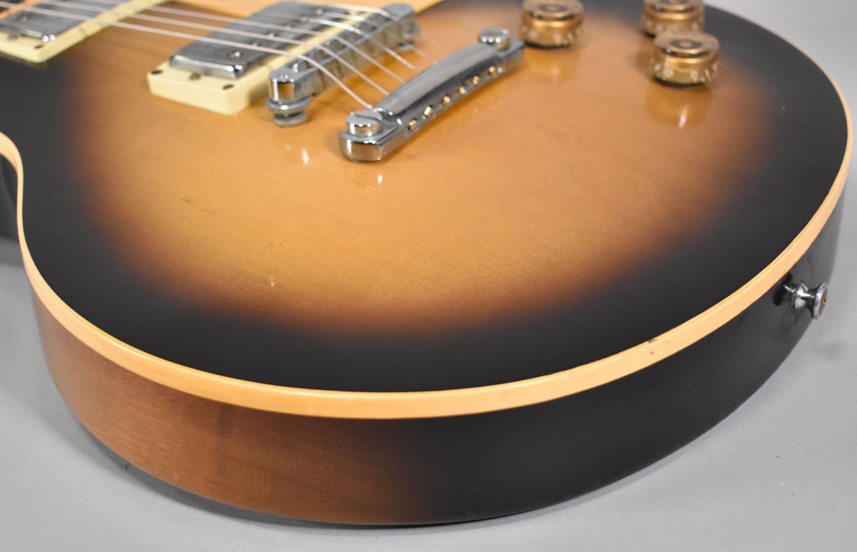 Close-up of the lower bout, showing the tobacco sunburst finish, cream binding, chrome bridge, and four gold control knobs.