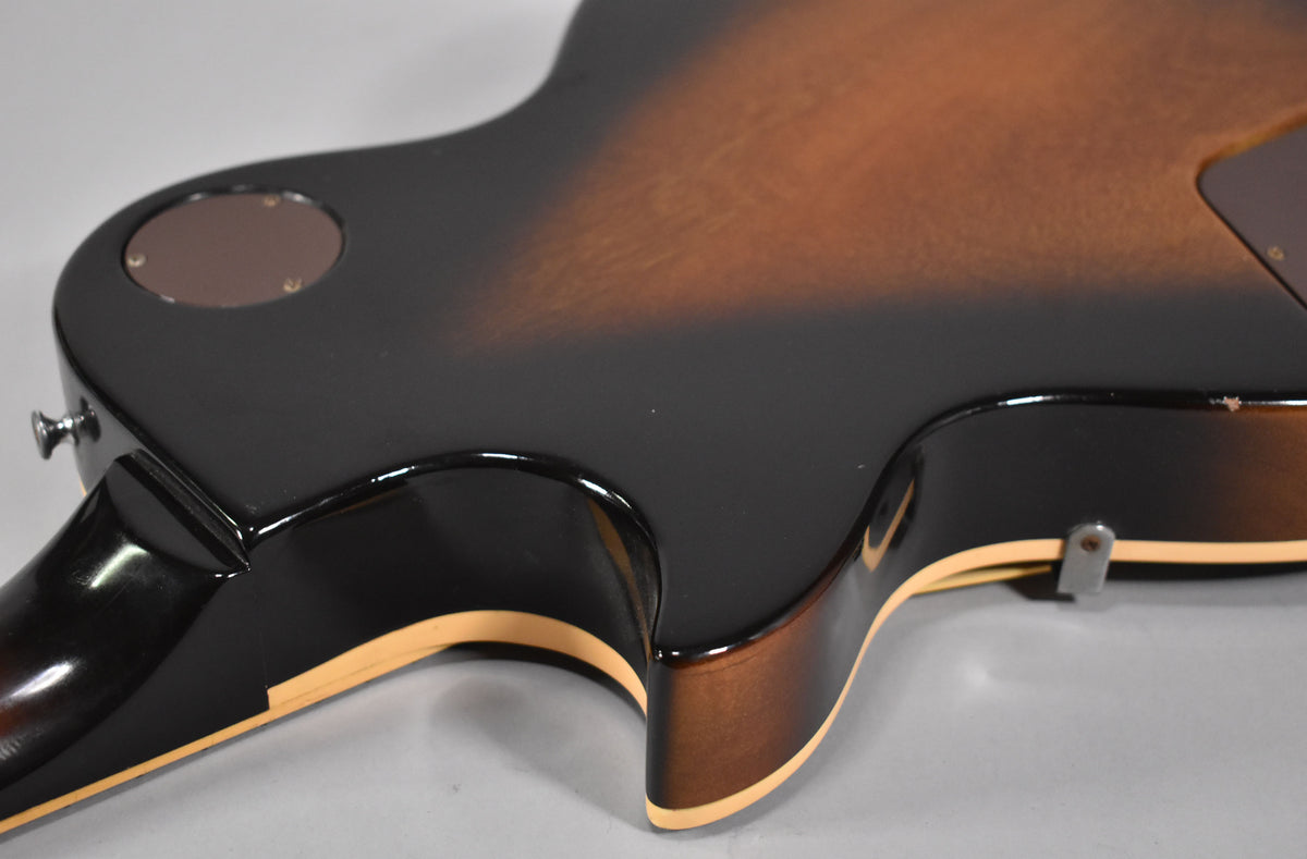 The lower bout and cutaway of a tobacco sunburst guitar, showing the neck joint, strap button, and control cavity cover.