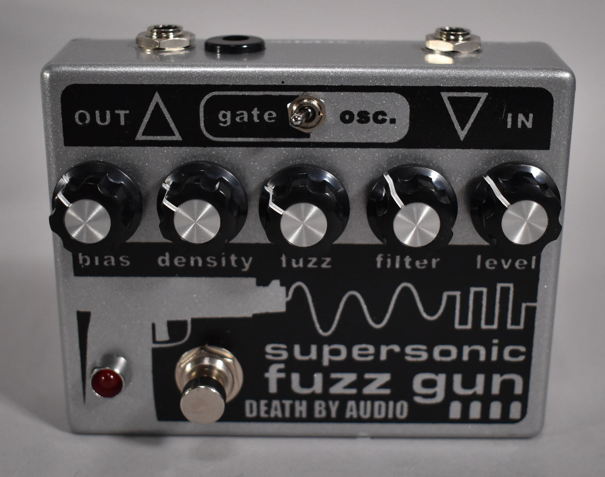 A silver guitar pedal with a black graphic panel, five black control knobs, a footswitch, and a red indicator light.