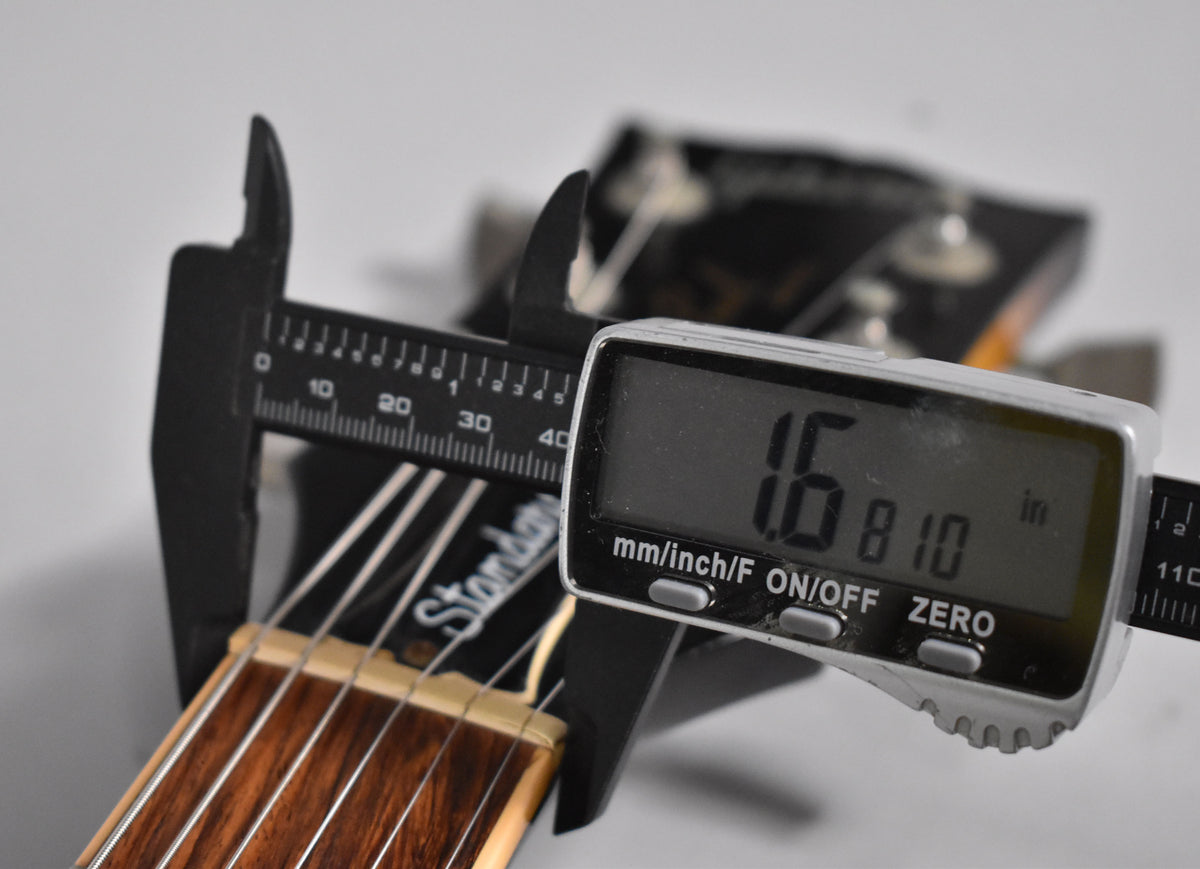 A digital caliper measures the guitar's nut width at 1.6810 inches, with a dark rosewood fretboard and bone nut visible.
