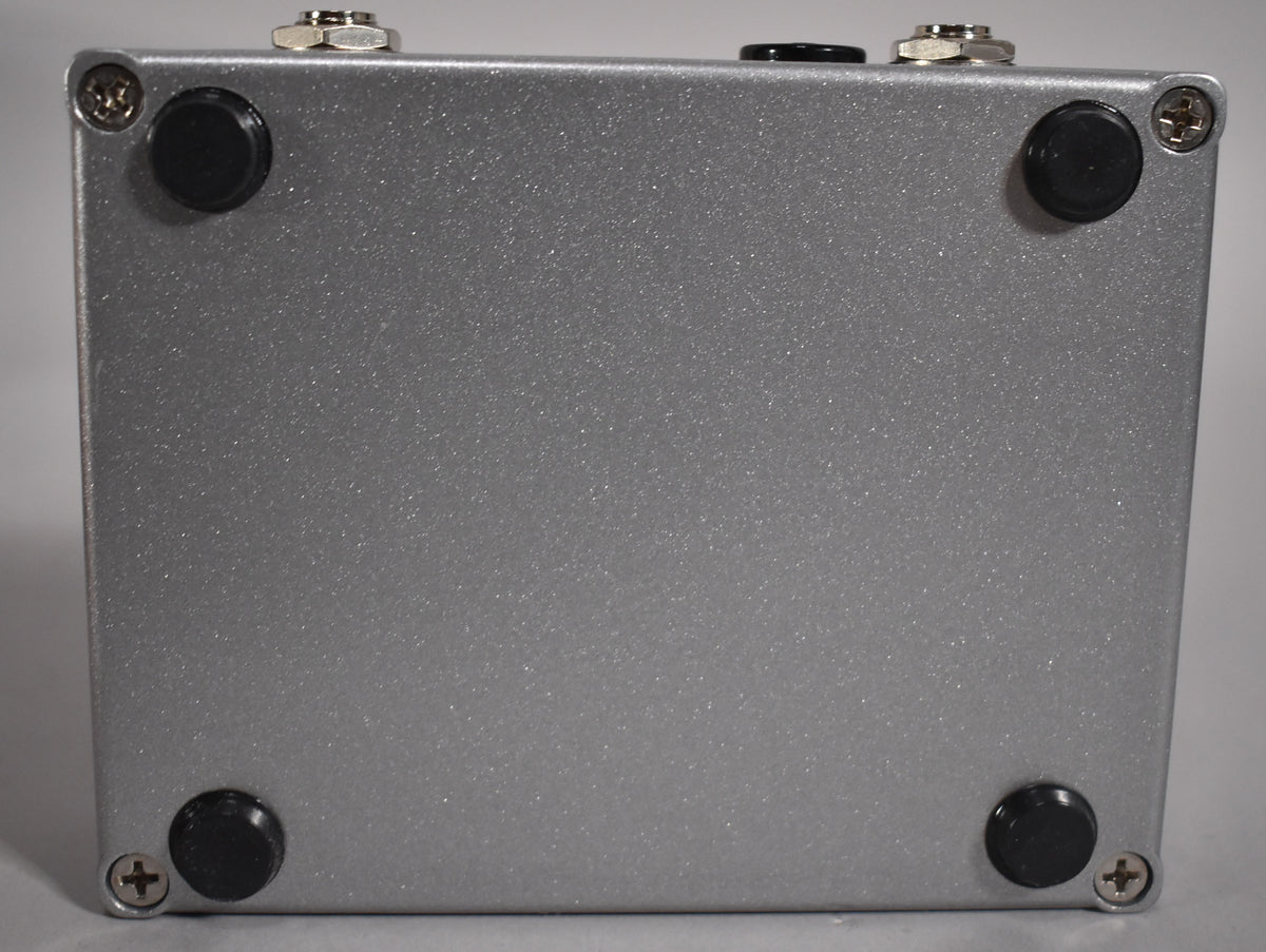 The pedal's bottom is silver with a glittery finish, showing four black rubber feet and four silver Phillips head screws.