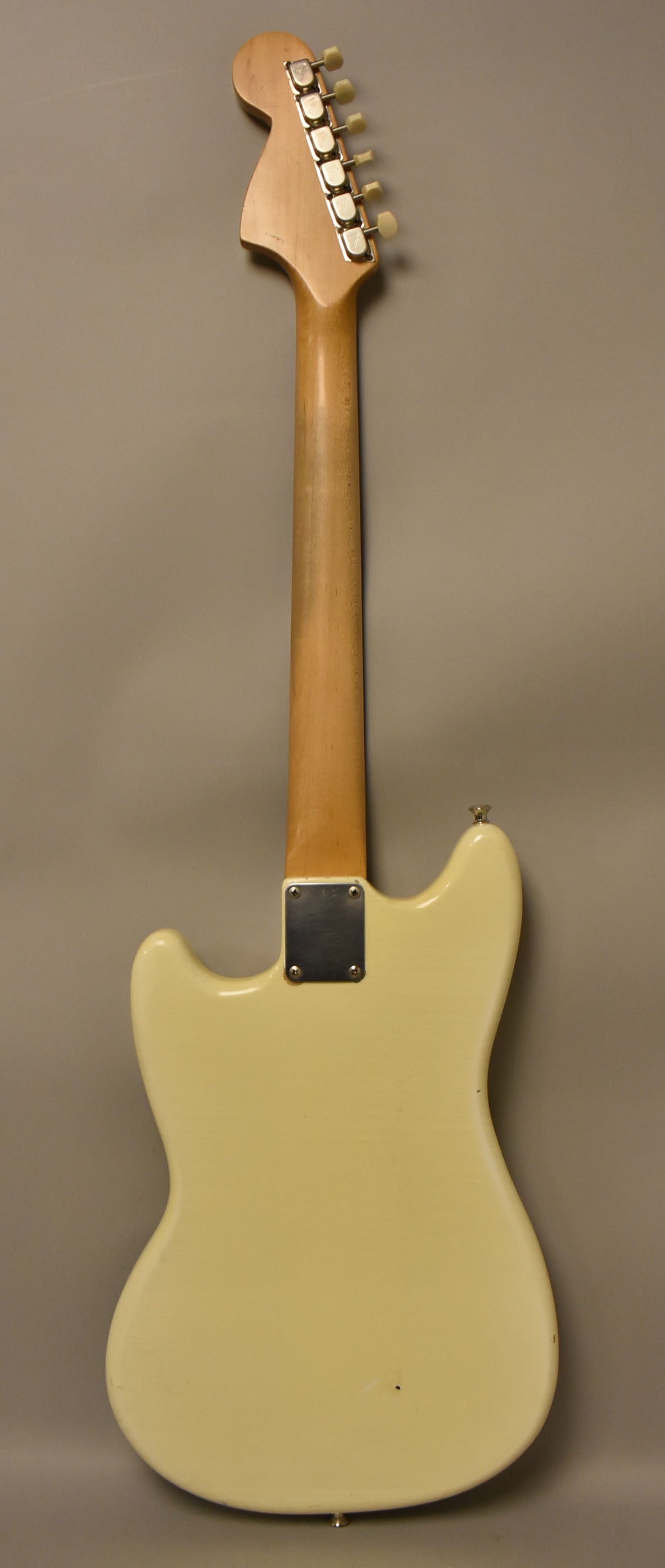 The guitar's back is shown, with a light-colored body, a natural wood neck, and six chrome tuners with cream buttons.