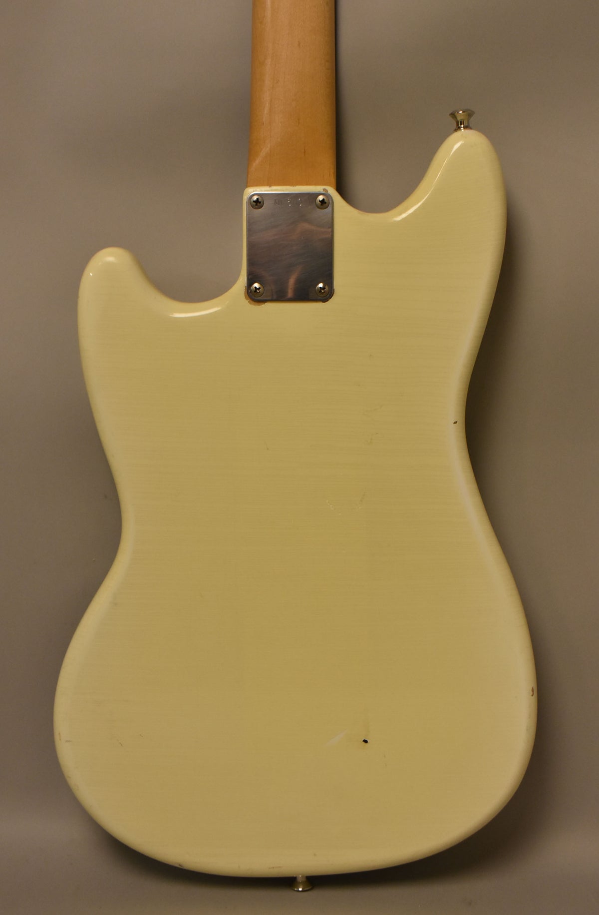 The back of an Olympic White guitar body, showing a neck plate, strap buttons, and light relic wear with a small chip.