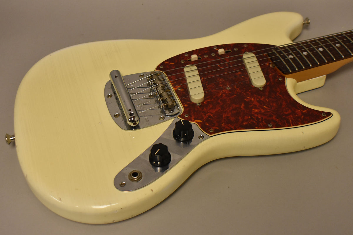 Olympic White electric guitar, angled from the lower bout, showing a tortoiseshell pickguard, two single-coil pickups, and a vibrato tailpiece.