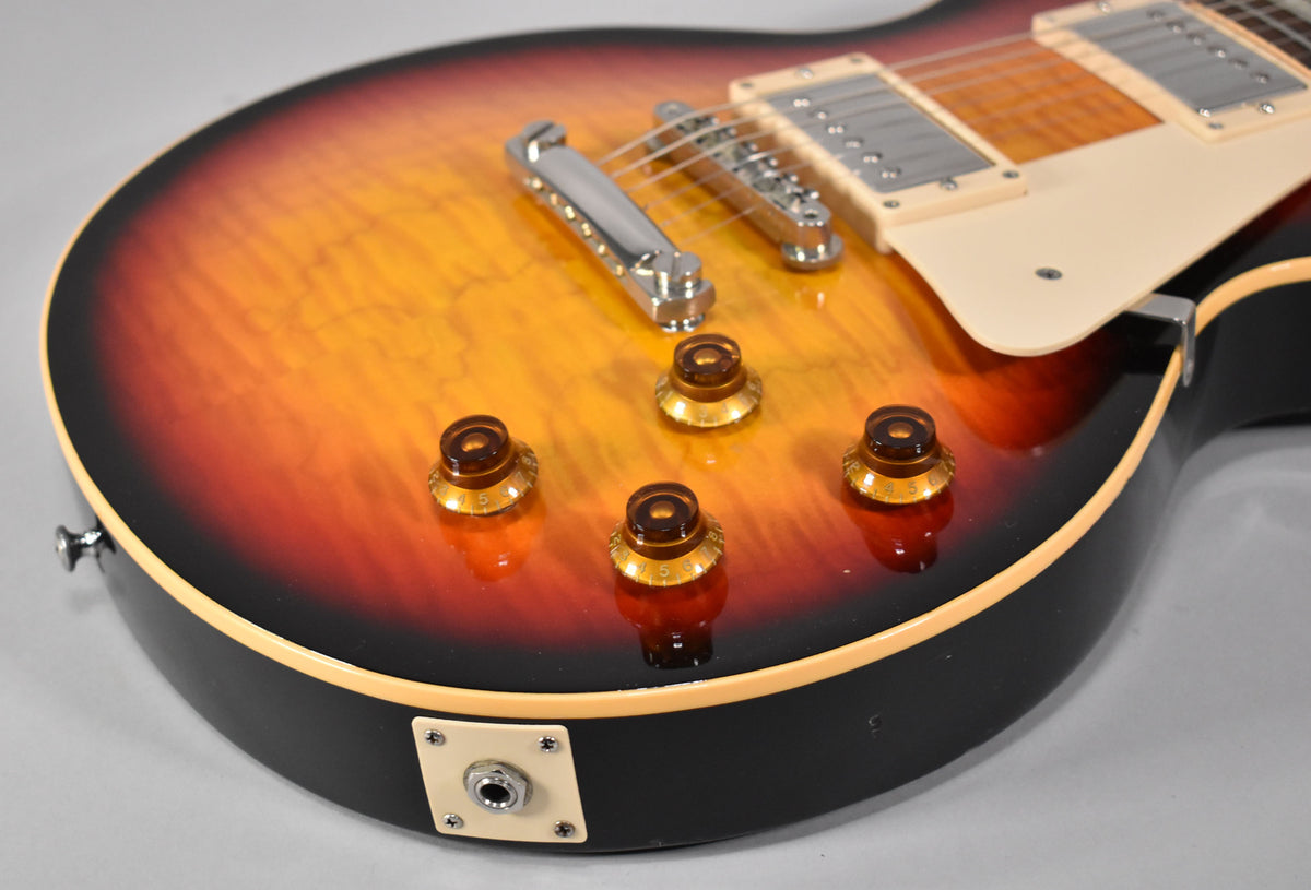 Close-up of the guitar's lower body, showing the Tri-Burst finish, four amber control knobs, chrome bridge, and cream output jack plate.
