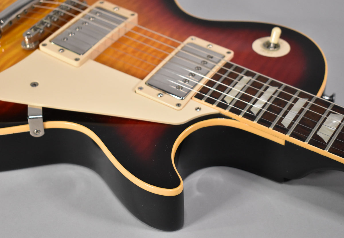 Close-up of the guitar's lower bout, showing the Tri-Burst finish, cream binding, pickguard, and trapezoid fretboard inlays.