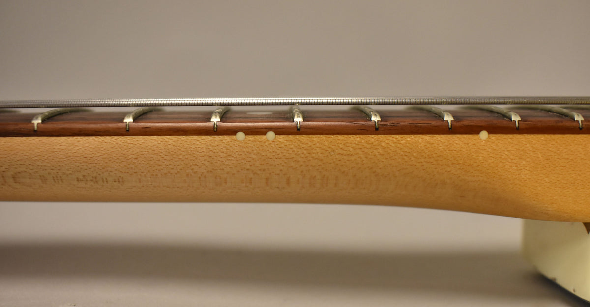 Close-up of the guitar's neck and rosewood fretboard, showing side dot markers and light wood grain on the neck.