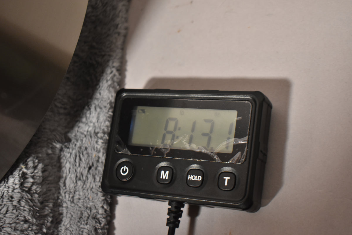The resonator's round, brushed steel body is partially visible on the left, next to a digital scale displaying "8.13" with a cracked screen protector.