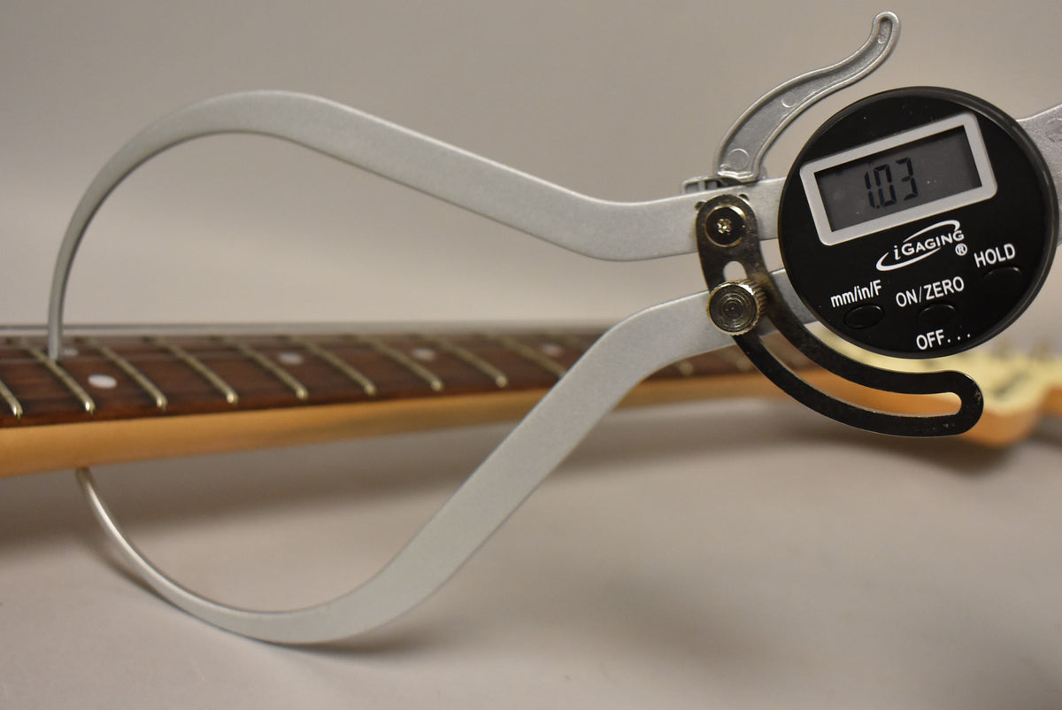 A digital caliper measures the guitar's fret height at 1.03mm, showing the dark rosewood fretboard and light maple neck.