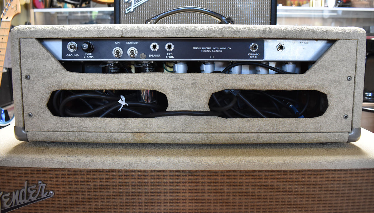 Rear view of the blond amp head, showing the black control panel with various inputs and switches, and two large cutouts revealing internal wiring.