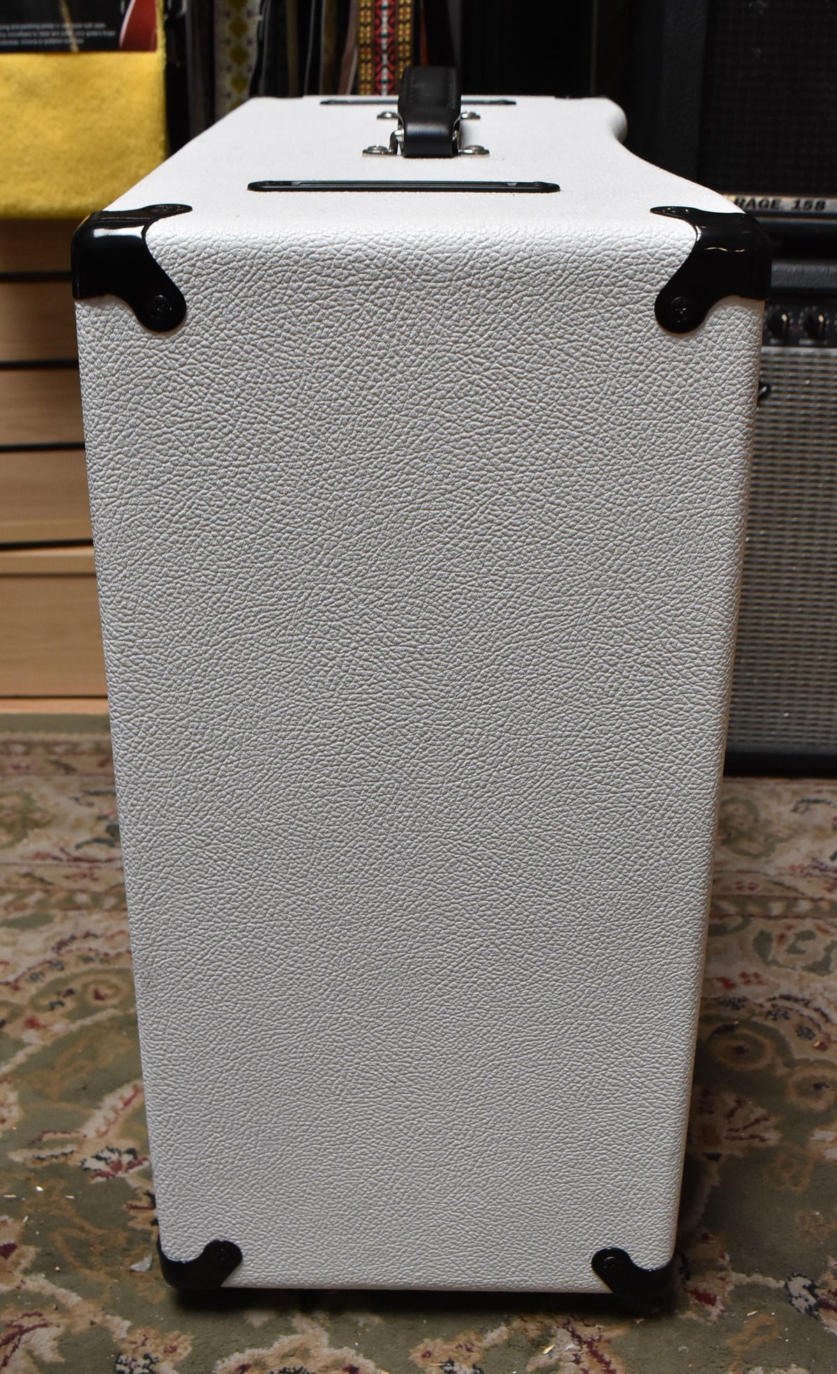 The white textured combo amp is viewed from the right side, showing black corner protectors and a black top handle.