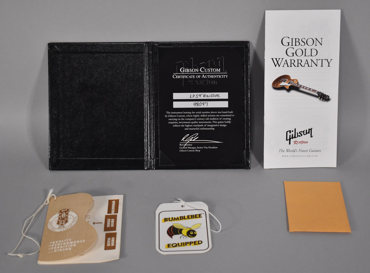 Top-down view of a black certificate of authenticity folder, a white warranty booklet, and three hang tags.