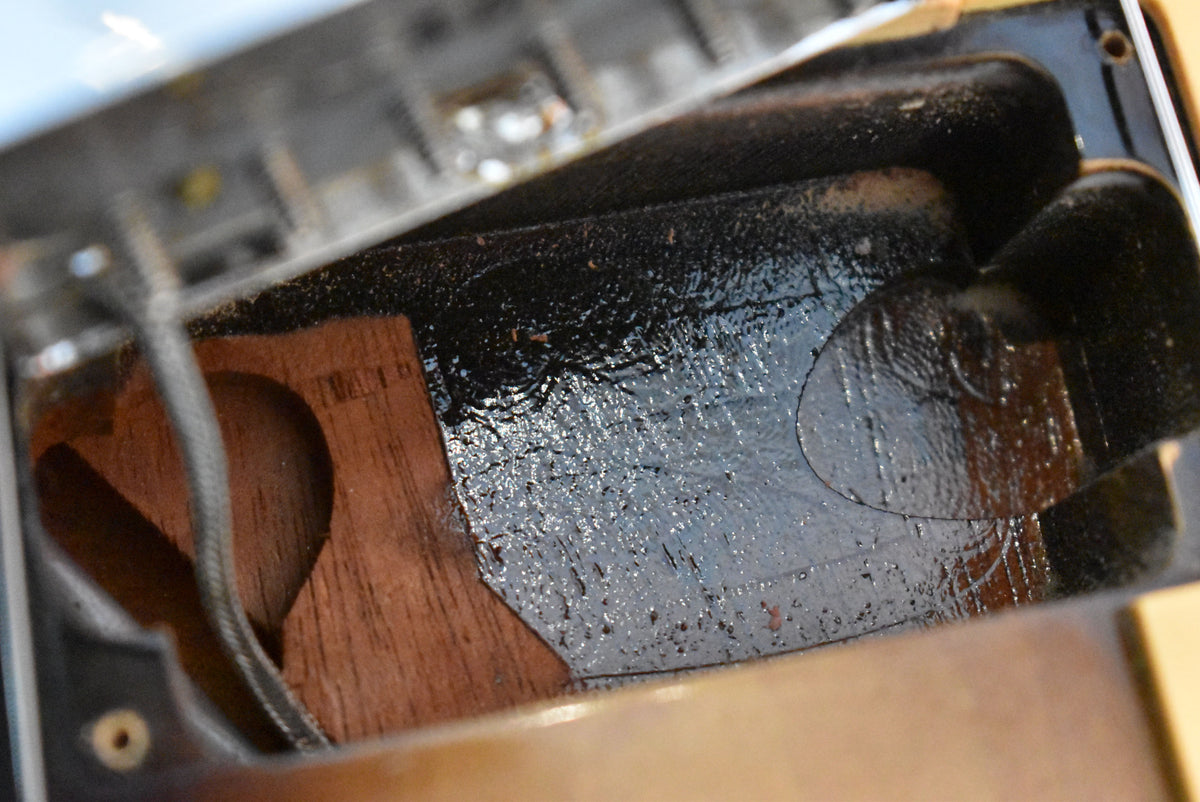 Close-up of the guitar's control cavity, showing rough black shielding paint and exposed mahogany wood with a visible serial number.