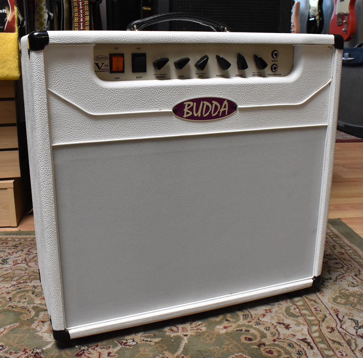 Front view of a white textured combo amp with a light gray speaker grille, black corner protectors, and a row of black knobs.