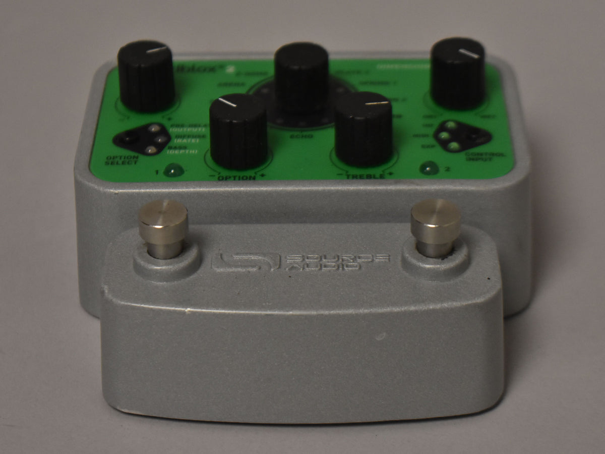 A gray pedal with a green top panel, five black knobs, two silver footswitches, and minor scuffs on the housing.