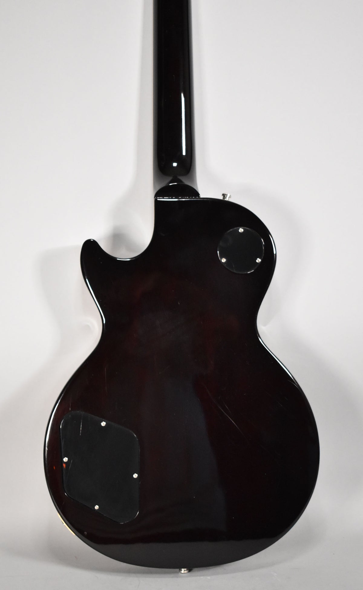 The back of the dark cherry sunburst guitar body and neck, showing light scratches on the glossy finish and two black control plates.