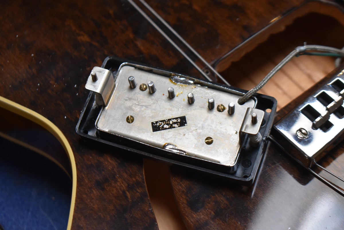 Close-up of the guitar's dark walnut body, showing the underside of a removed pickup with exposed wiring and a chrome bridge.