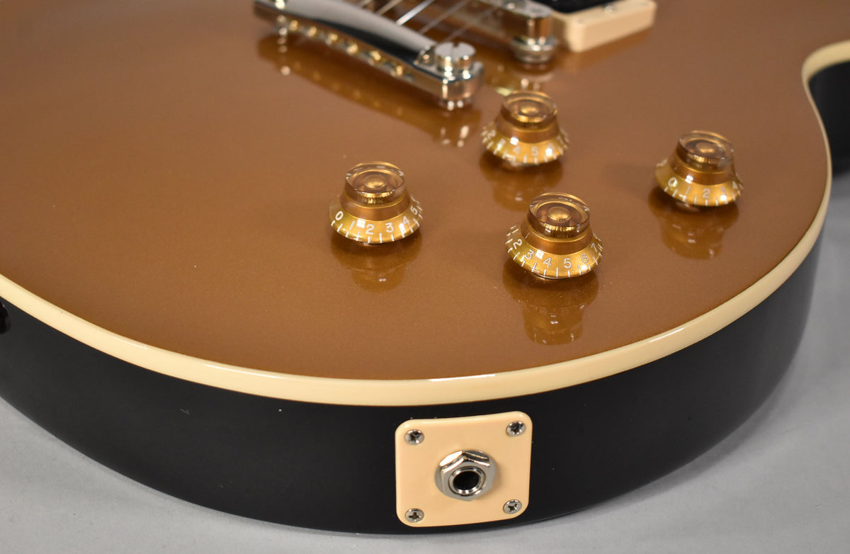 Close-up of the Goldtop body, showing four amber top hat knobs, cream binding, and the cream output jack plate on the black side.