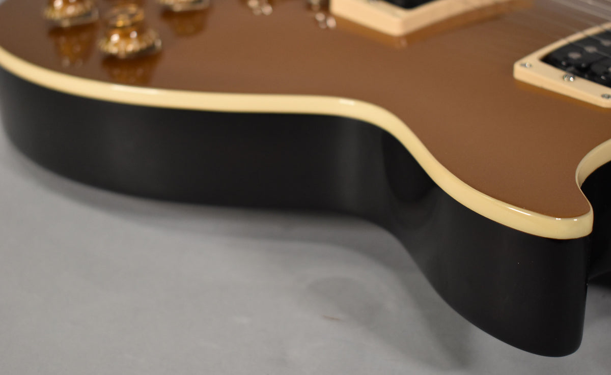 Close-up of the guitar's lower bout, showing the glossy goldtop finish, cream binding, and black sides with no visible wear.