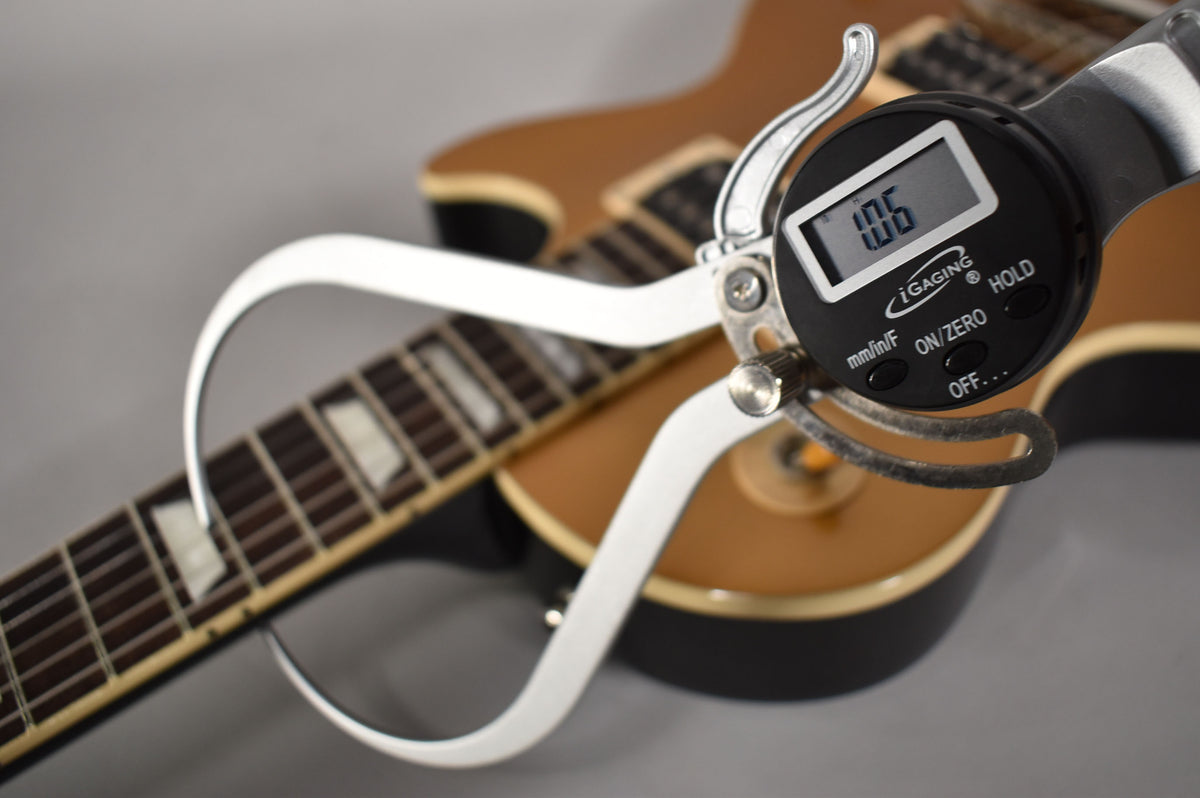A digital caliper measures the fret height at 1.06mm on the dark fretboard of the goldtop Les Paul.