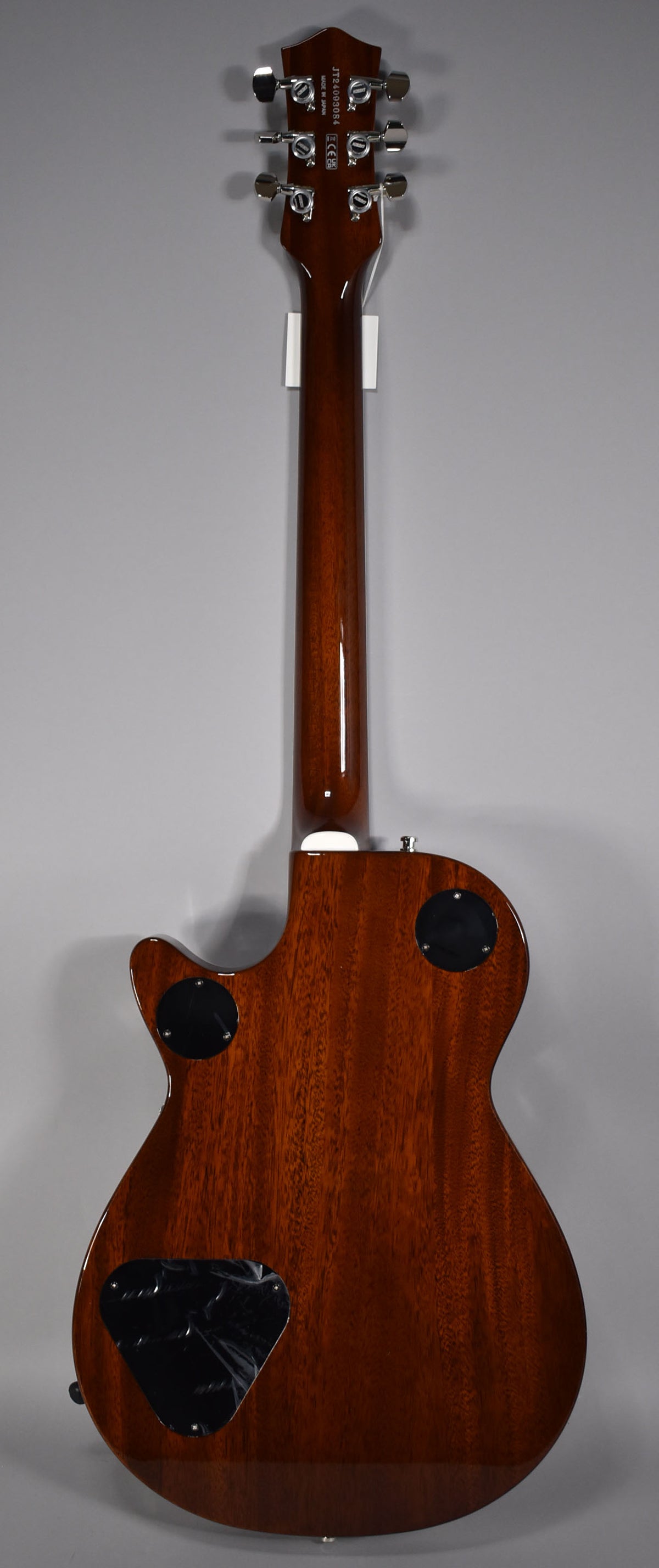 The guitar's back, neck, and headstock are visible, all in a glossy dark brown finish with chrome tuners and black control covers.