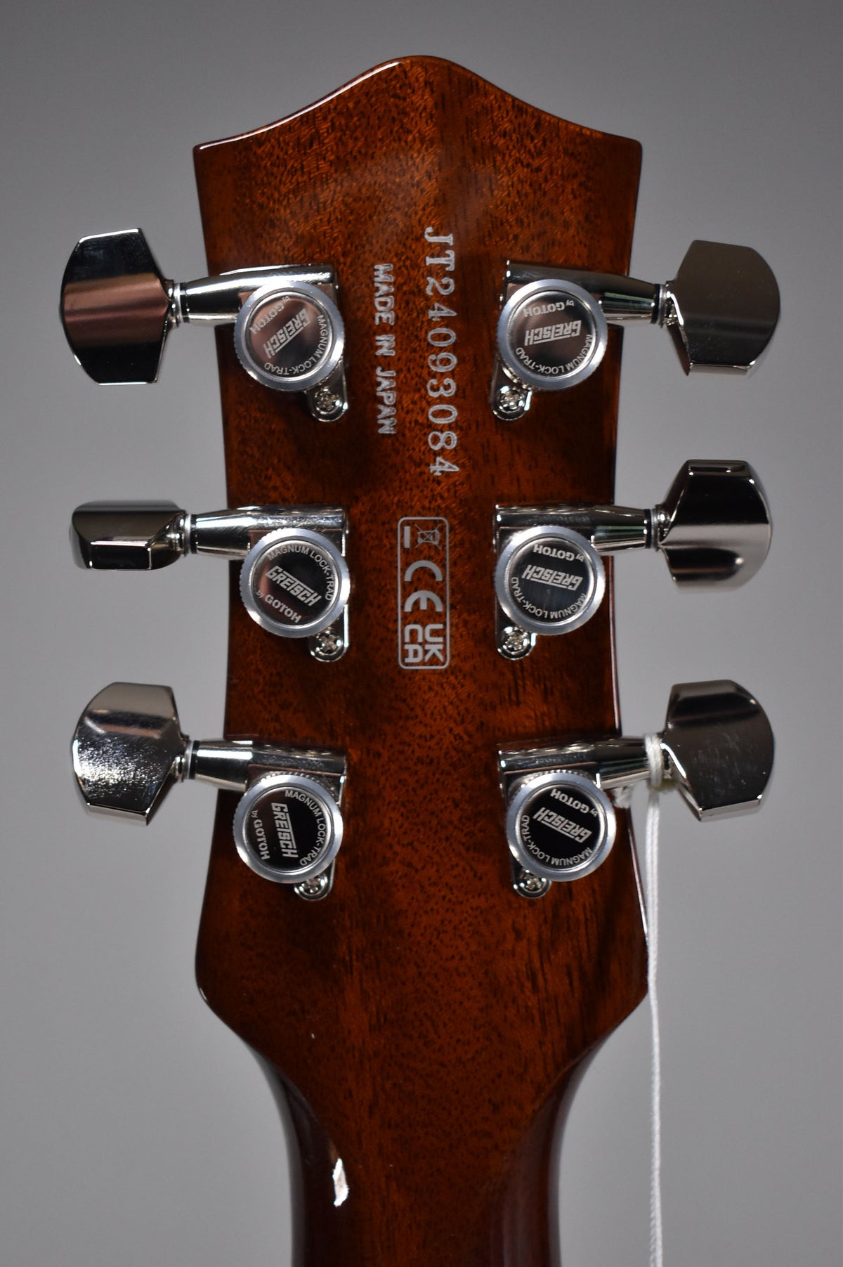 The guitar's dark brown headstock, viewed from the rear, features six chrome tuning pegs with "Gretsch by Gotoh" stamped on them.
