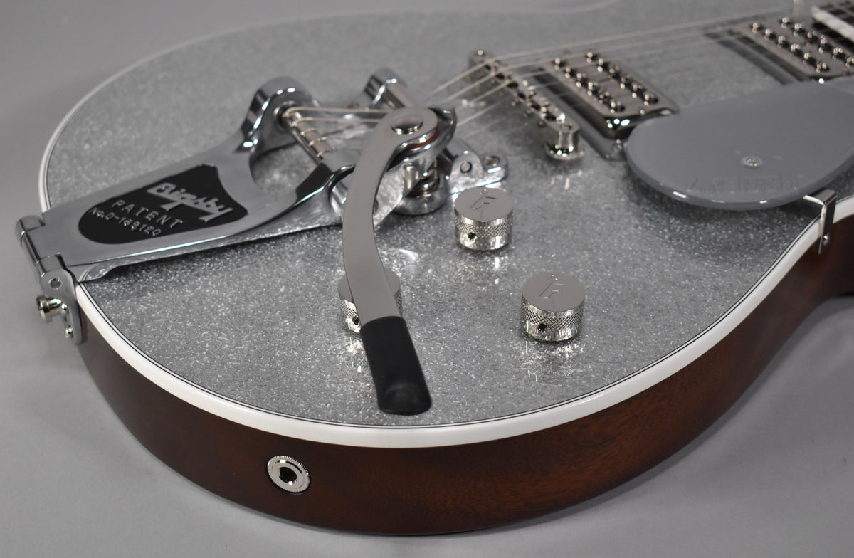 Close-up of the lower bout, showing the silver sparkle top, Bigsby vibrato, two knurled chrome control knobs, and output jack.