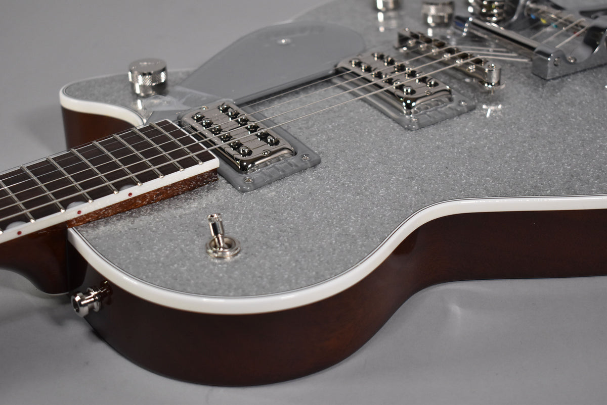 Close-up of the silver sparkle body with white binding, dark brown sides, chrome pickups, and a three-way toggle switch.