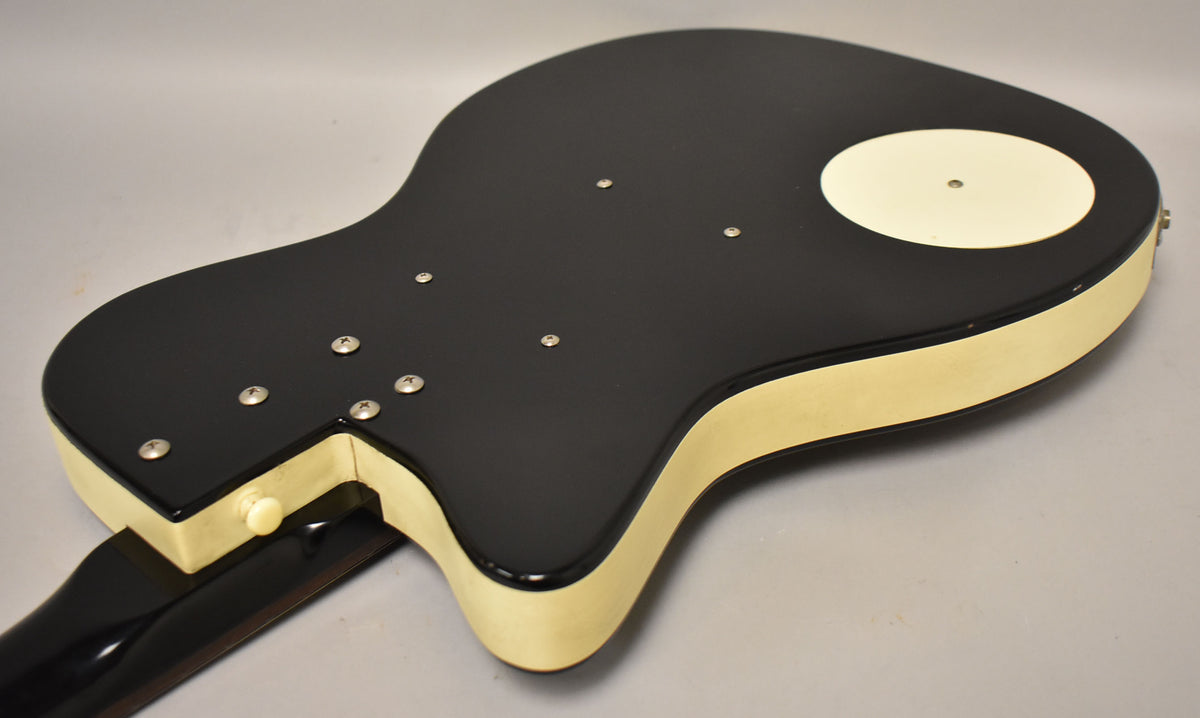 The guitar's black back and sides are visible, with a cream-colored binding and a circular cream access plate.