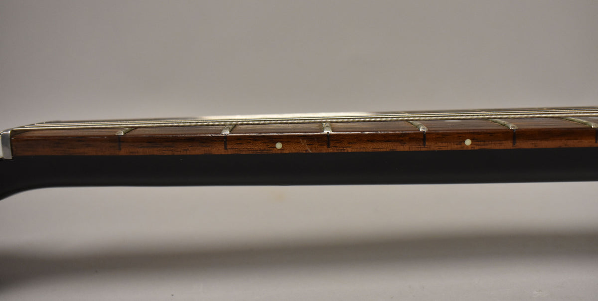 Close-up of the dark brown fretboard with white dot inlays, showing light wear and a few scratches.