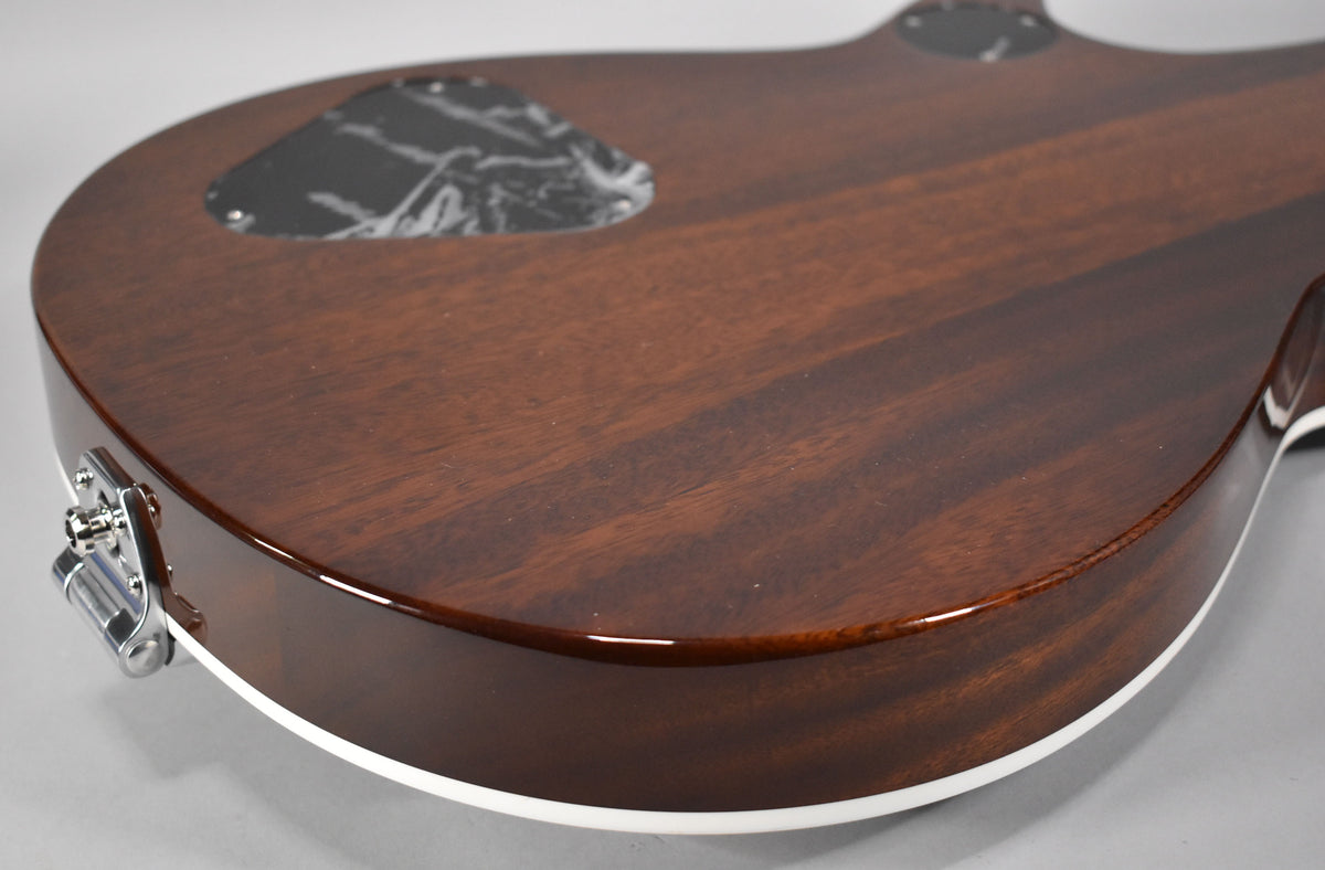 The guitar's dark brown back and side are visible, with a white binding strip and a chrome strap button on the lower bout.