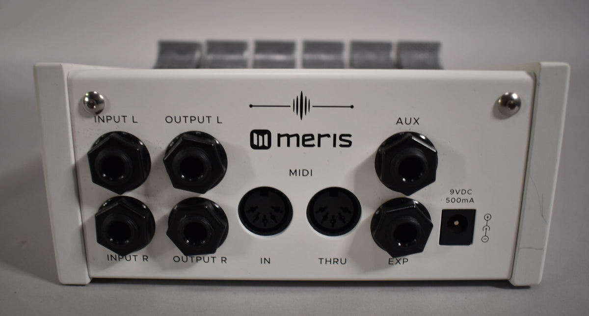 Rear view of the white pedal, showing eight black 1/4" jacks, two MIDI ports, and a power input, with minor scuffs.